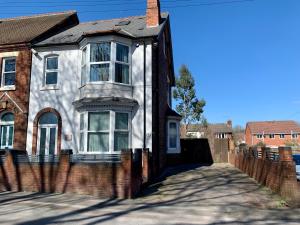une maison en briques avec une clôture devant elle dans l'établissement Somerford Place - 6 Beds - Sleeps 12 - Parks 2-3 cars/vans, à Willenhall