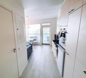 a kitchen with white cabinets and a room with a table at New Studio Furi near Airport in Vantaa