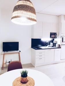 eine weiße Küche mit einem Tisch und einer Topfpflanze in der Unterkunft New Studio Furi near Airport in Vantaa