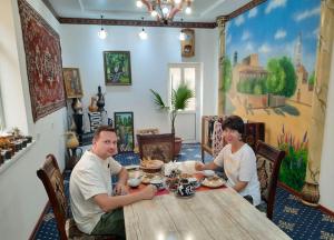 a man and woman sitting at a wooden table at Guest House Khiva ,, BOYJON OTA " in Khiva