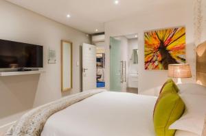 a white bedroom with a large bed and a tv at 107 Dorpstraat Boutique Hotel in Stellenbosch