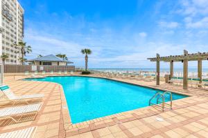 ein Swimmingpool mit Stühlen und der Strand im Hintergrund in der Unterkunft Shoalwater 804 in Orange Beach