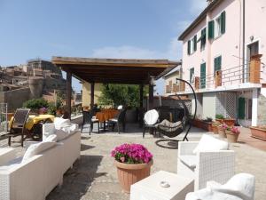 patio z białymi wiklinowymi krzesłami i stołami w obiekcie Giglio Castello - alloggi Mario & Marta w mieście Isola del Giglio