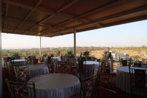 a room with tables and chairs with a view of a field at Blisss Hotel Kolhapur in Kolhapur