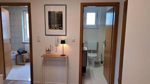 a bathroom with a toilet and a table with a lamp at Ferienwohnungen Sachsenblick in Grafenau