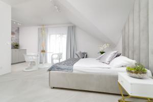 a white bedroom with a bed and a table at Apartamenty Lambert Grzybowo in Grzybowo
