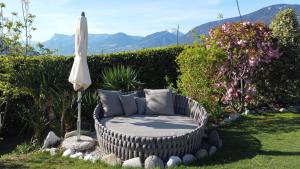 - une chaise en osier avec un parasol dans le jardin dans l'établissement Hotel Garni Herz, à Tirolo
