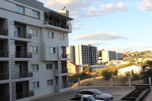 a white apartment building with a car parked in a parking lot at Abigail's Studio Apartment @ Trift Tower in Windhoek
