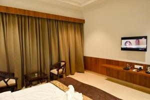 a hotel room with a bed and a flat screen tv at MD FARMS AND RESORTS in Mathura