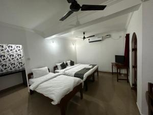 a room with two beds and a ceiling fan at Ocean Way Guest House in Baga