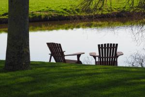 two chairs sitting next to a body of water at Hoeve BuytenHout in Delft