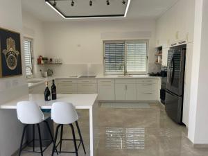a kitchen with white cabinets and white stools at הבית הלבן in Qiryat Shemona