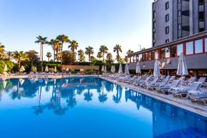 a swimming pool with lounge chairs and umbrellas at A11 Hotel Obaköy in Alanya