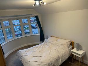 a bedroom with a bed in a room with windows at Super Convenient 2 Double Bed apartment for Central London - 30 seconds walk to platform train station and 19 mins to London Waterloo in London