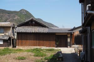 une maison en bois avec une montagne en arrière-plan dans l'établissement 岡邸, à Tonosho