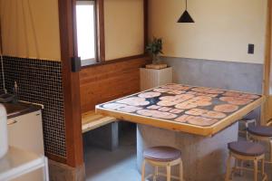 - une cuisine avec une table et des tabourets dans une pièce dans l'établissement 岡邸, à Tonosho