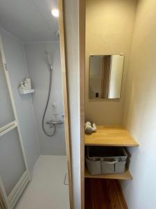 La salle de bains est pourvue d'un lavabo, d'un miroir et d'une douche. dans l'établissement 岡邸, à Tonosho