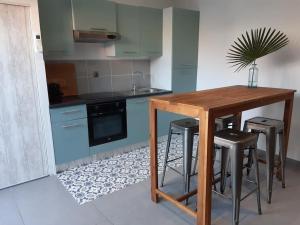 a kitchen with blue cabinets and a wooden table and stools at Grand studio avec patio in Marseille