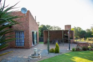 a garden with a brick house with a courtyard at East of East Guest Cottage in Avondzon
