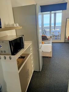um pequeno quarto com um frigorífico, uma cama e uma mesa em Studio Vue Mer 100 m de la plage em Port Leucate