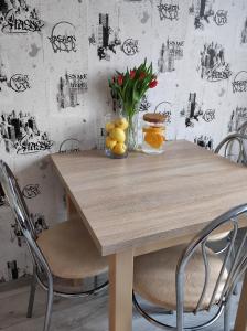 einen Holztisch mit Stühlen und eine Vase aus Obst in der Unterkunft TROFFI T14- SELF CHECK-IN apartment for your comfort in Mažeikiai