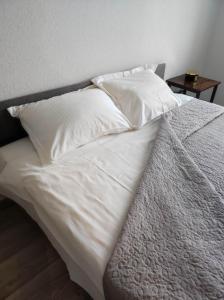 ein Bett mit weißer Bettwäsche und Kissen darauf in der Unterkunft TROFFI T14- SELF CHECK-IN apartment for your comfort in Mažeikiai