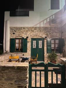 una casa in pietra con porte e finestre verdi di Pension Sofia Amorgos a Katápola