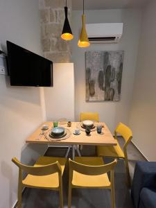 uma mesa de jantar com cadeiras amarelas e uma televisão em Egusa73 Favignana em Favignana