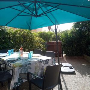 a table with a blue umbrella on a patio at appartement 6p rez-de-jardin clim accés mer direct in Le Barcarès