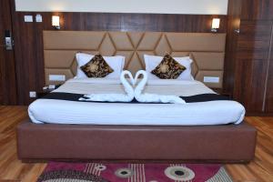 Hotel Bhagyaraj Palace - Best Hotel In Kanpur في كانبور: وجود اثنين من البجعات البيضاء فوق السرير