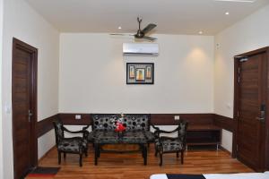 Hotel Bhagyaraj Palace - Best Hotel In Kanpur في كانبور: غرفة معيشة مع أريكة وكرسيين