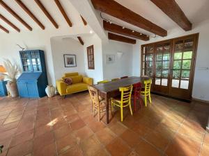 a living room with a wooden table and yellow chairs at Spacious Villa with Pool and Fireplace in Roquebrune-sur-Argens