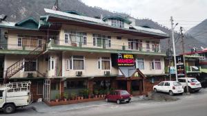um edifício com uma carrinha vermelha estacionada em frente em Mahesh Hotel em Rāmpur