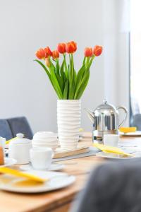 una mesa con un jarrón con tulipanes rojos. en Ferienwohnungen im Haus Deichnest, en Bensersiel