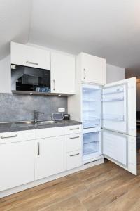 cocina con armarios blancos, fregadero y nevera en Ferienwohnungen im Haus Deichnest, en Bensersiel