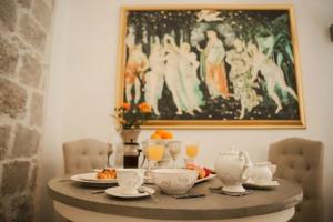 a table with plates and cups and a painting on the wall at Elephant in my room in Dubrovnik
