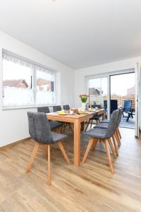 a dining room with a wooden table and chairs at Ferienwohnungen im Haus Deichnest in Bensersiel