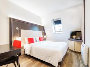 Habitación de hotel con cama, escritorio y TV. en Hôtel de Bonlieu en Annecy