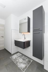 bagno bianco con lavandino e specchio di Ferienwohnungen im Haus Deichnest a Bensersiel