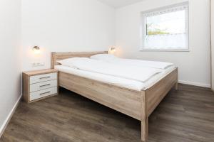 1 cama en un dormitorio con marco de madera y ventana en Ferienwohnungen im Haus Deichnest en Bensersiel