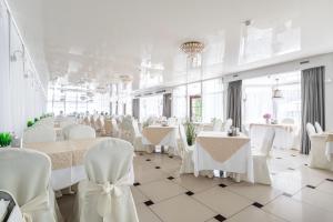 スヴェトロゴルスクにあるVolna Hotelの白いテーブルと白い椅子が備わる宴会場