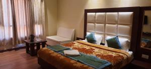 um quarto com uma cama grande e uma cadeira em Mahesh Hotel em Rāmpur