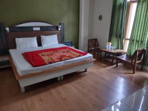 um quarto com uma cama com um cobertor vermelho em Mahesh Hotel em Rāmpur
