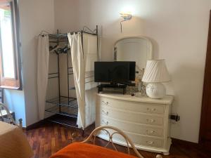 una camera da letto con cassettiera, TV e specchio di B&B Federica a Cagliari