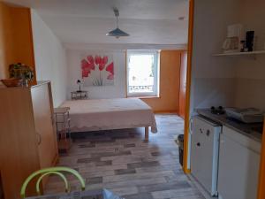a room with a bed and a kitchen with a window at Les Logis du Haut-Folin in Arleuf
