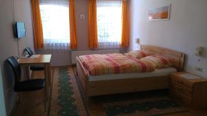 een slaapkamer met een bed, een bureau en 2 ramen bij Gasthaus zum Goldenen Roß in Creglingen
