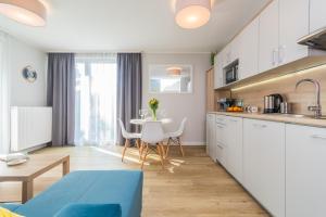 eine Küche und ein Wohnzimmer mit einem Tisch und Stühlen in der Unterkunft Apartamenty NCNK Stegna Forest in Stegna