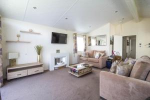 a living room with a couch and a fireplace at Luxury 6 Berth Lodge With Wifi At Broadland Sands In Suffolk Ref 20011cv in Hopton on Sea