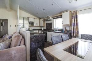 a kitchen and living room with a table and chairs at Luxury 6 Berth Lodge With Wifi At Broadland Sands In Suffolk Ref 20011cv in Hopton on Sea