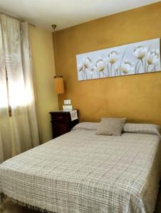 een slaapkamer met een bed en een schilderij aan de muur bij Casita de ensueño en Ronda in Ronda